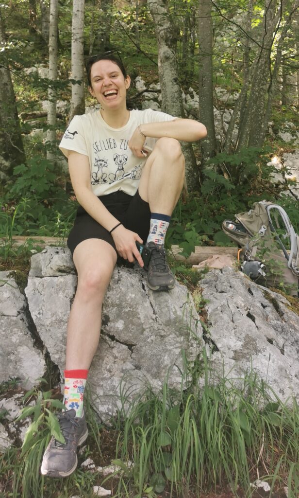 Vanessa sitzt lachend auf einem Stein